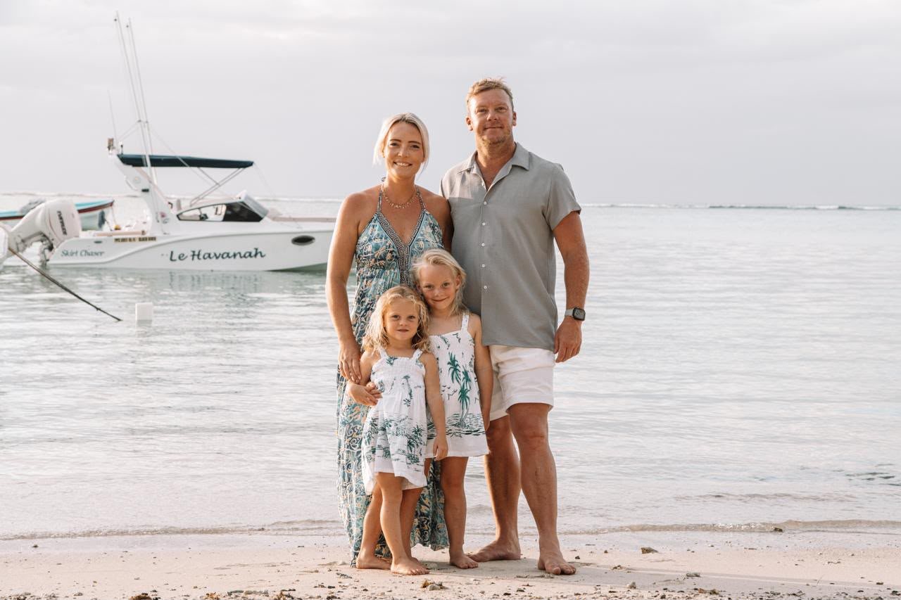 Sam with her husband Janco and their daughters standing together on the beach